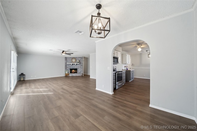 unfurnished living room featuring visible vents, dark wood finished floors, arched walkways, a textured ceiling, and a large fireplace