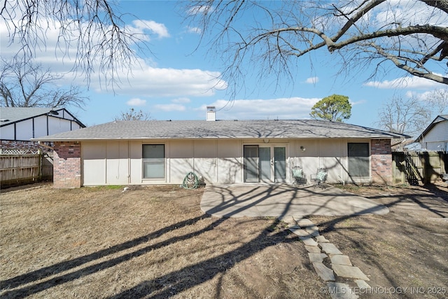 rear view of house featuring a patio, brick siding, a chimney, and fence