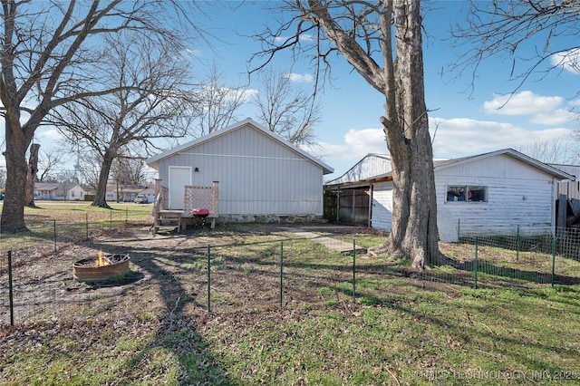 rear view of property featuring an outbuilding and fence