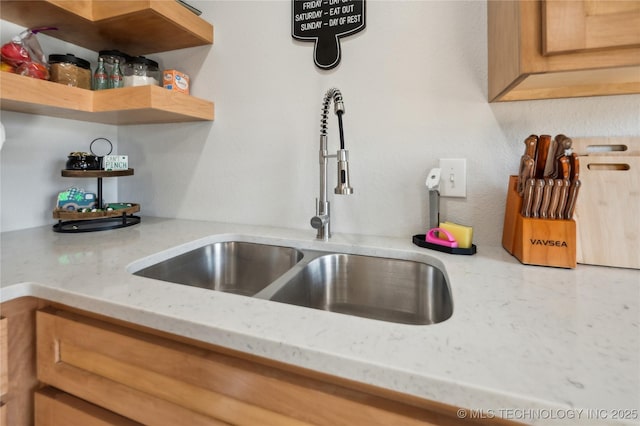 details with light stone countertops, open shelves, and a sink