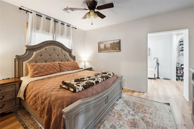 bedroom featuring a ceiling fan, visible vents, and wood finished floors