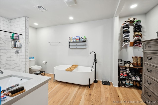 full bathroom with visible vents, a soaking tub, wood finished floors, vanity, and recessed lighting