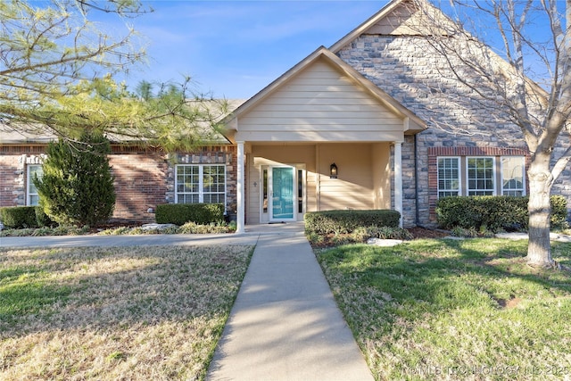 view of front of home with a front yard, stone siding, and brick siding