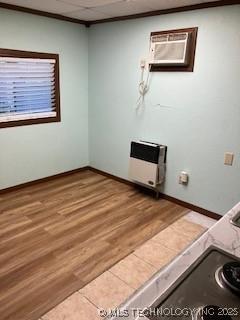 interior space with laundry area, baseboards, light wood-style flooring, and heating unit