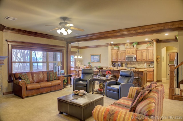 living room with arched walkways, ceiling fan, light colored carpet, visible vents, and crown molding