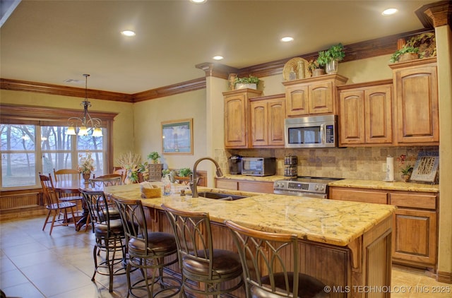 kitchen with a breakfast bar, tasteful backsplash, appliances with stainless steel finishes, a sink, and light stone countertops