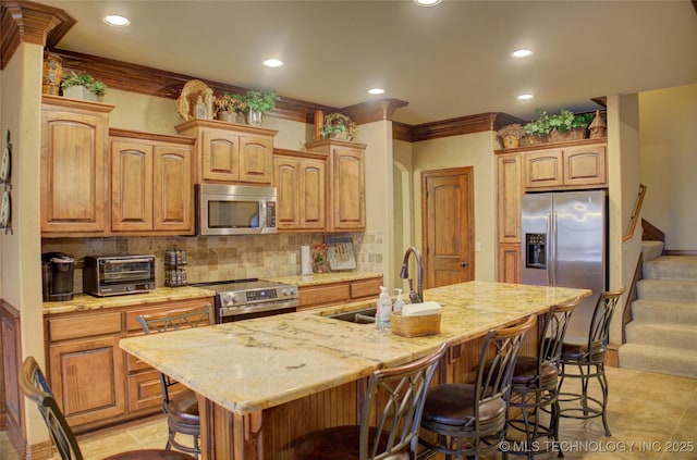 kitchen with a toaster, tasteful backsplash, a breakfast bar area, appliances with stainless steel finishes, and a sink