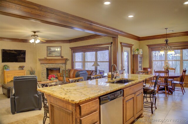 kitchen featuring stainless steel dishwasher, a fireplace, a sink, and a breakfast bar