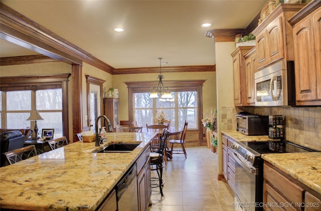 kitchen featuring light stone counters, stainless steel appliances, backsplash, a sink, and a kitchen breakfast bar