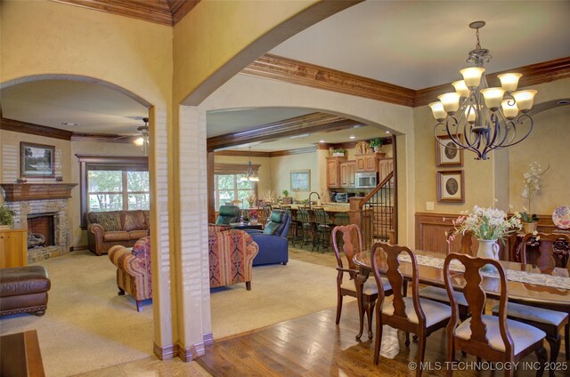 3402 Harbour Town Pl, Claremore, OK 74019 - dining space with a chandelier, light colored carpet, arched walkways, a ceiling fan, and ornamental molding