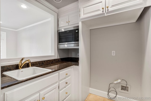 11630 S Fulton Ave, Tulsa, OK 74137 - kitchen featuring stainless steel microwave, a sink, white cabinets, ornamental molding, and dark stone countertops