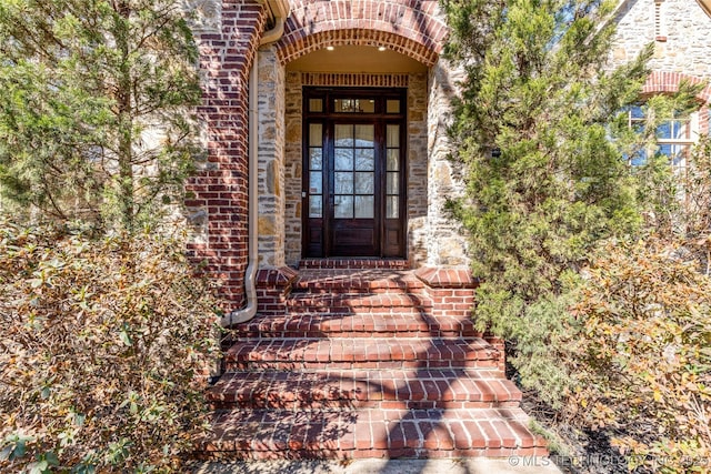 entrance to property featuring stone siding and brick siding