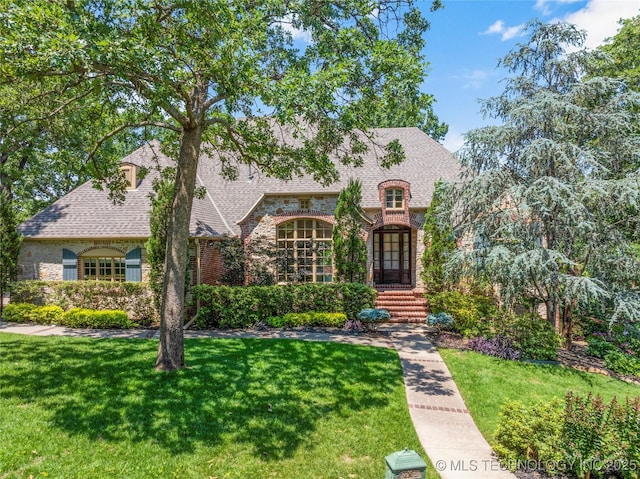 11630 S Fulton Ave, Tulsa, OK 74137 - tudor home featuring a front yard, brick siding, a shingled roof, and stone siding