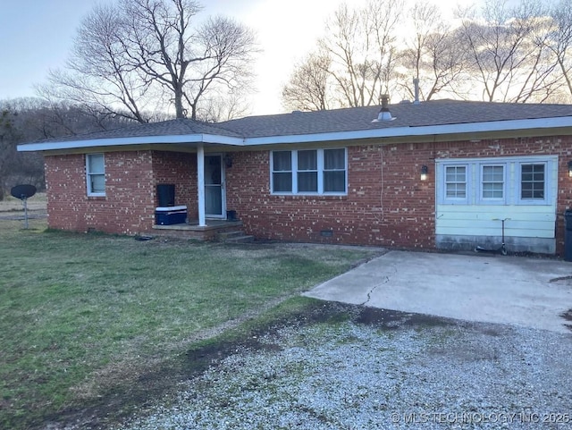 view of front facade featuring a patio, brick siding, crawl space, a front lawn, and gravel driveway