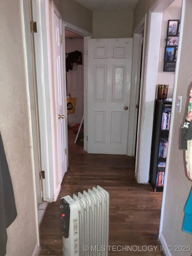 hall with radiator heating unit and wood finished floors