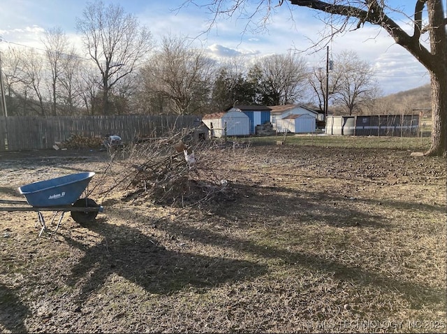 view of yard with fence, an outdoor structure, and a storage unit