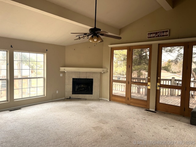 unfurnished living room with vaulted ceiling with beams, visible vents, a tiled fireplace, carpet flooring, and baseboards