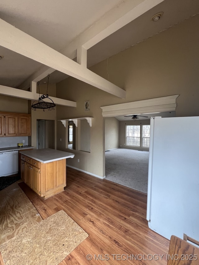 kitchen with white appliances, a ceiling fan, open floor plan, beamed ceiling, and wood finished floors