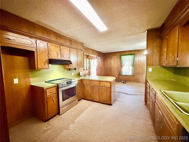 kitchen featuring under cabinet range hood, a peninsula, a sink, light countertops, and stainless steel electric stove