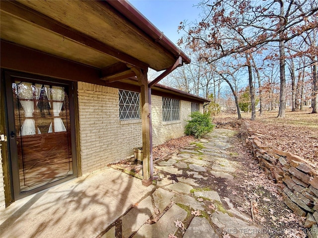 view of side of home with a patio area and brick siding