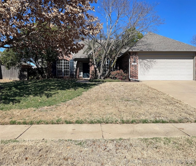 ranch-style home with an attached garage, brick siding, concrete driveway, roof with shingles, and a front yard