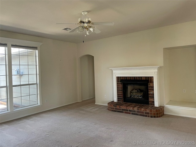 unfurnished living room featuring a fireplace, visible vents, arched walkways, and carpet flooring