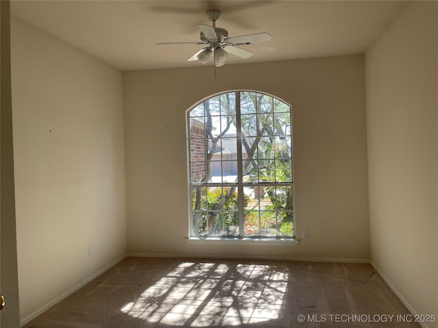 carpeted spare room with a ceiling fan and baseboards