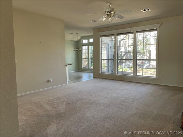 carpeted spare room featuring plenty of natural light, visible vents, and ceiling fan