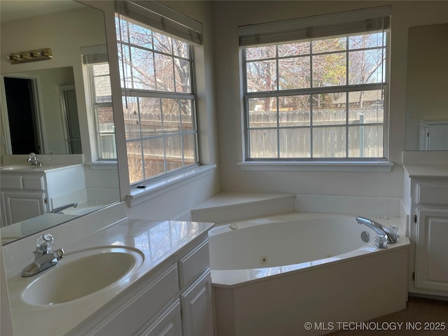 bathroom with a whirlpool tub, plenty of natural light, and a sink