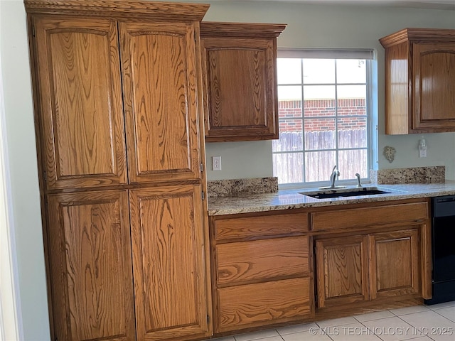 kitchen with light tile patterned floors, light stone counters, a sink, brown cabinets, and dishwasher