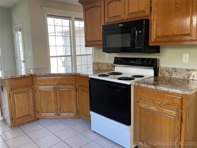 kitchen with a peninsula, light stone countertops, black microwave, and range with electric stovetop