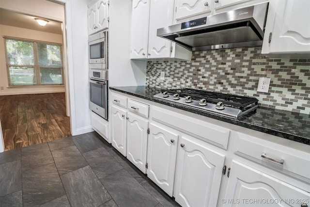 kitchen featuring stainless steel appliances, range hood, white cabinetry, and tasteful backsplash