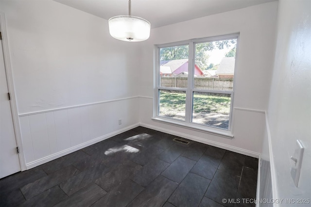 empty room with a wainscoted wall and visible vents