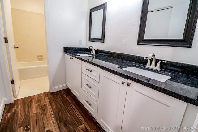 full bathroom with double vanity, a sink, and wood finished floors