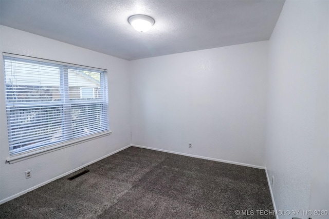 unfurnished room featuring a textured ceiling, dark carpet, visible vents, and baseboards