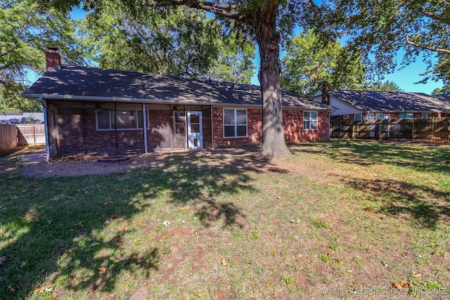 single story home featuring brick siding, a chimney, a front yard, and fence