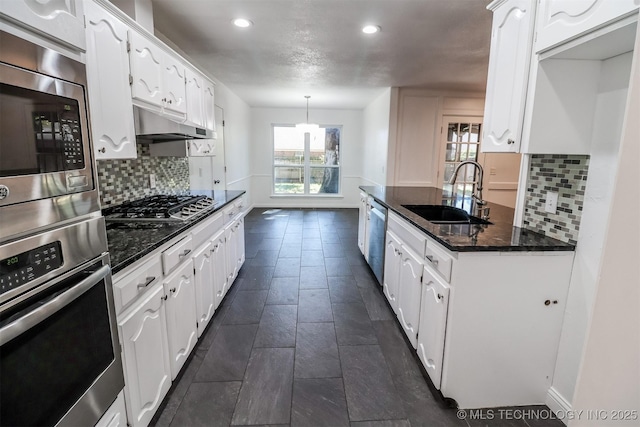 kitchen featuring white cabinets, under cabinet range hood, stainless steel appliances, and a sink