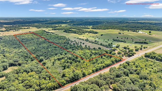 drone / aerial view featuring a view of trees and a rural view