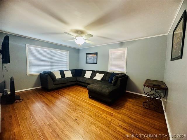 living area featuring baseboards, wood finished floors, and ornamental molding