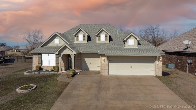 view of front of home with driveway, fence, a yard, roof with shingles, and brick siding