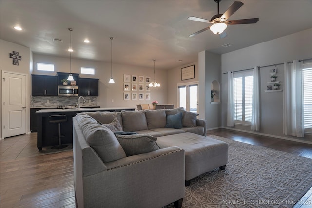 living area with plenty of natural light, dark wood-style floors, visible vents, and ceiling fan