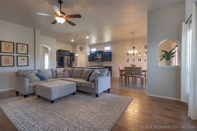 11923 E 105th Ct N, Owasso, OK 74055 - living room featuring dark wood-style floors, ceiling fan with notable chandelier, arched walkways, and baseboards