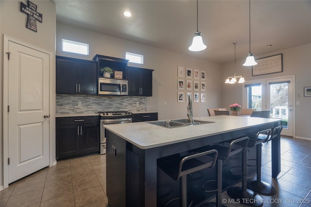 kitchen with a kitchen bar, a sink, backsplash, stainless steel appliances, and light countertops