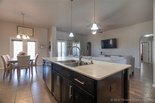 kitchen with a sink, open floor plan, arched walkways, light countertops, and hanging light fixtures