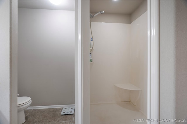 full bath featuring a shower, baseboards, toilet, and tile patterned flooring