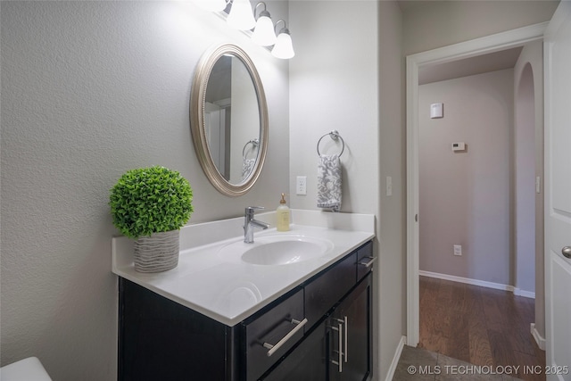 bathroom featuring baseboards, wood finished floors, and vanity