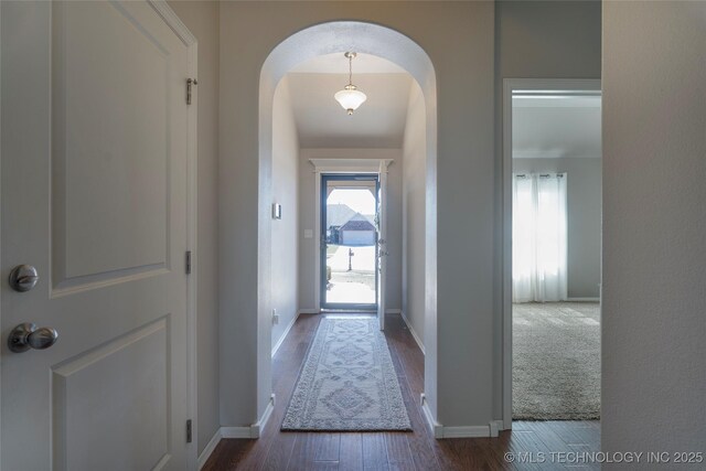11923 E 105th Ct N, Owasso, OK 74055 - doorway to outside featuring arched walkways, dark wood-type flooring, and baseboards
