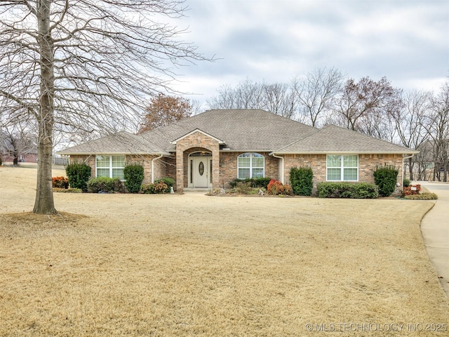 single story home with brick siding, roof with shingles, and a front yard