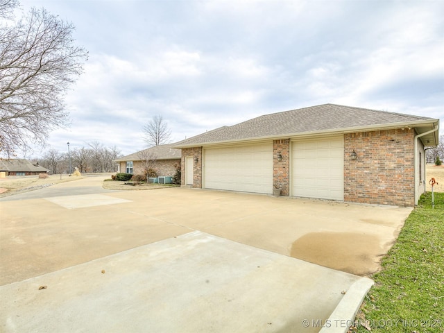 view of property exterior featuring a shingled roof, concrete driveway, brick siding, and an attached garage