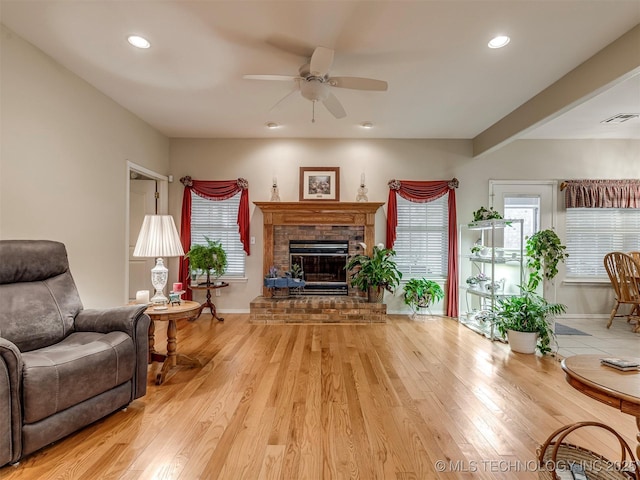 living room featuring light wood-style floors, a brick fireplace, visible vents, and recessed lighting